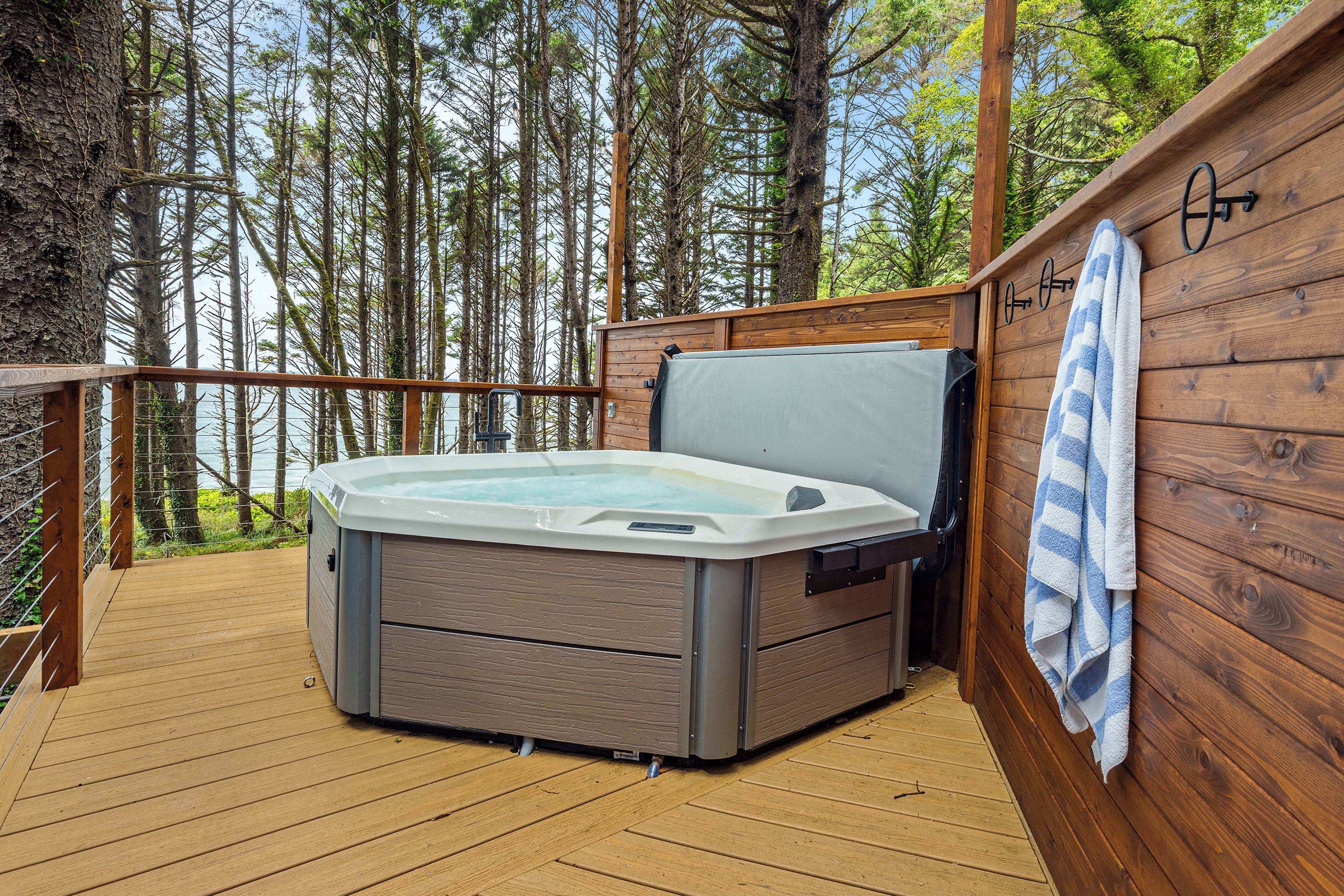 A hot tub on a wooden deck with a view of a forest.