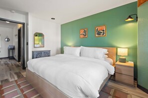 A hotel room with a large bed, a bedside table with a lamp, a mirror, and two wall art pieces. - Ocean Front, The Mighty Mussel House @ Betty's Beachside, Stairs to the Beach! (Yachats)