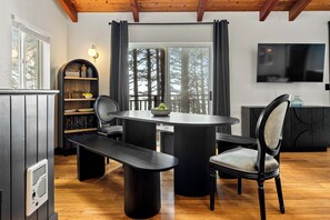 Et moderne spiseområde med et rundt bord, bænke og stole, en reol og et fjernsyn monteret på væggen.
