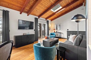 A modern living room with a wooden ceiling, a flat-screen TV, a sofa, a coffee table, and a lamp. - Ocean Front, The Mighty Mussel House @ Betty's Beachside, Stairs to the Beach! (Yachats)