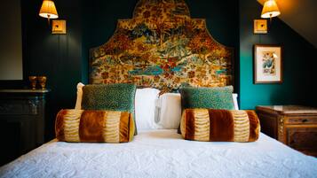 A bed with a patterned headboard, two wall-mounted lamps, and a framed picture on the wall.