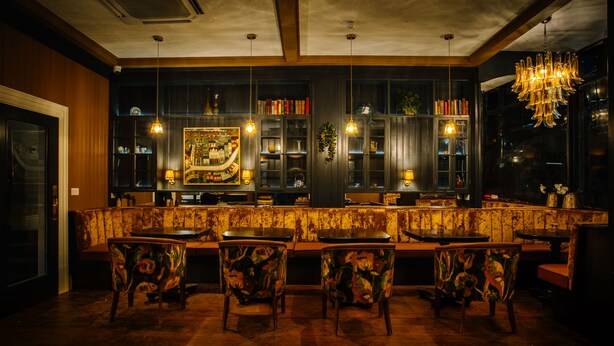 Un espace bar doté d’un plancher en bois, de tabourets de bar et de luminaires suspendus.
