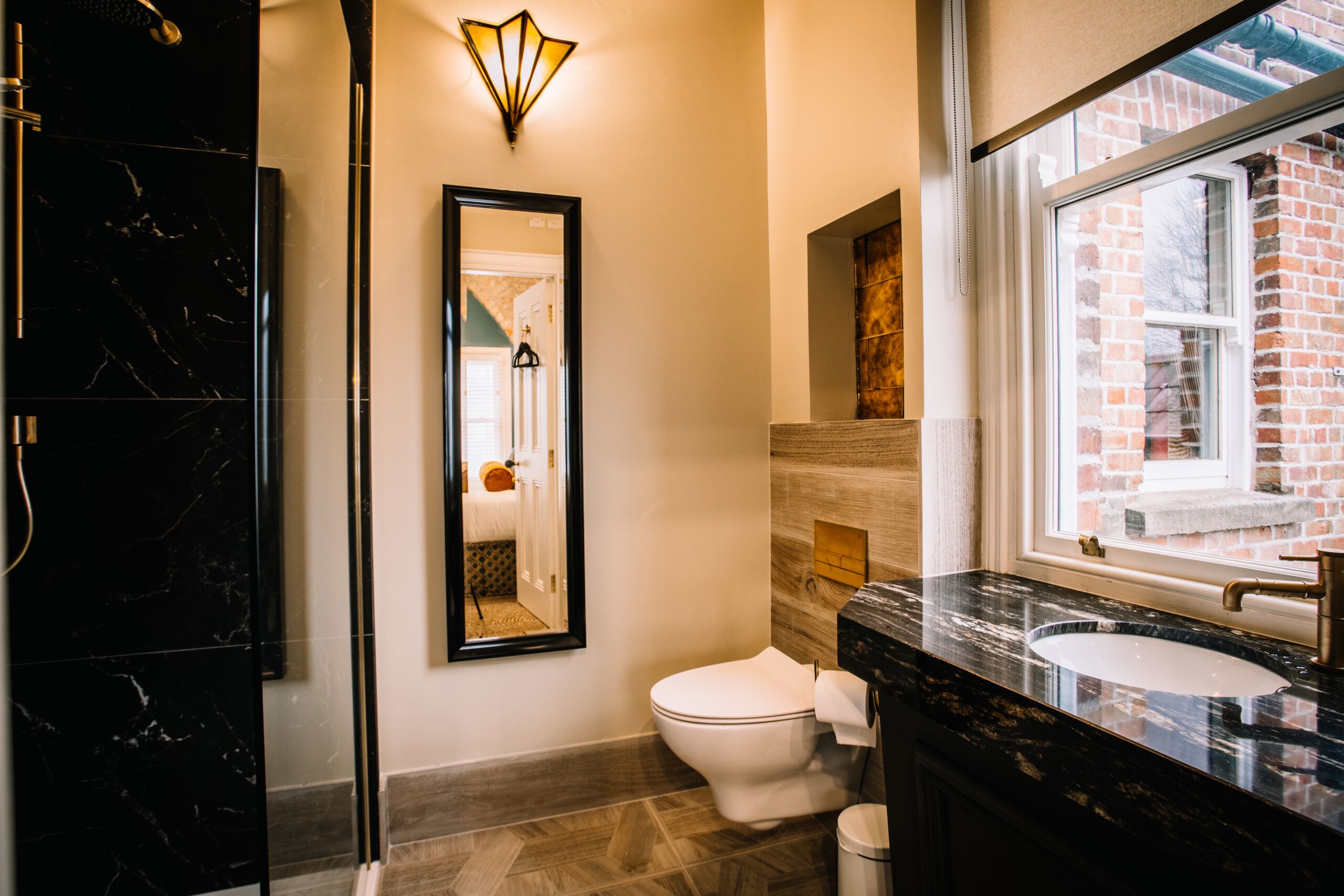 Een moderne badkamer met een zwart marmeren wastafelmeubel, een wit toilet en een spiegel.