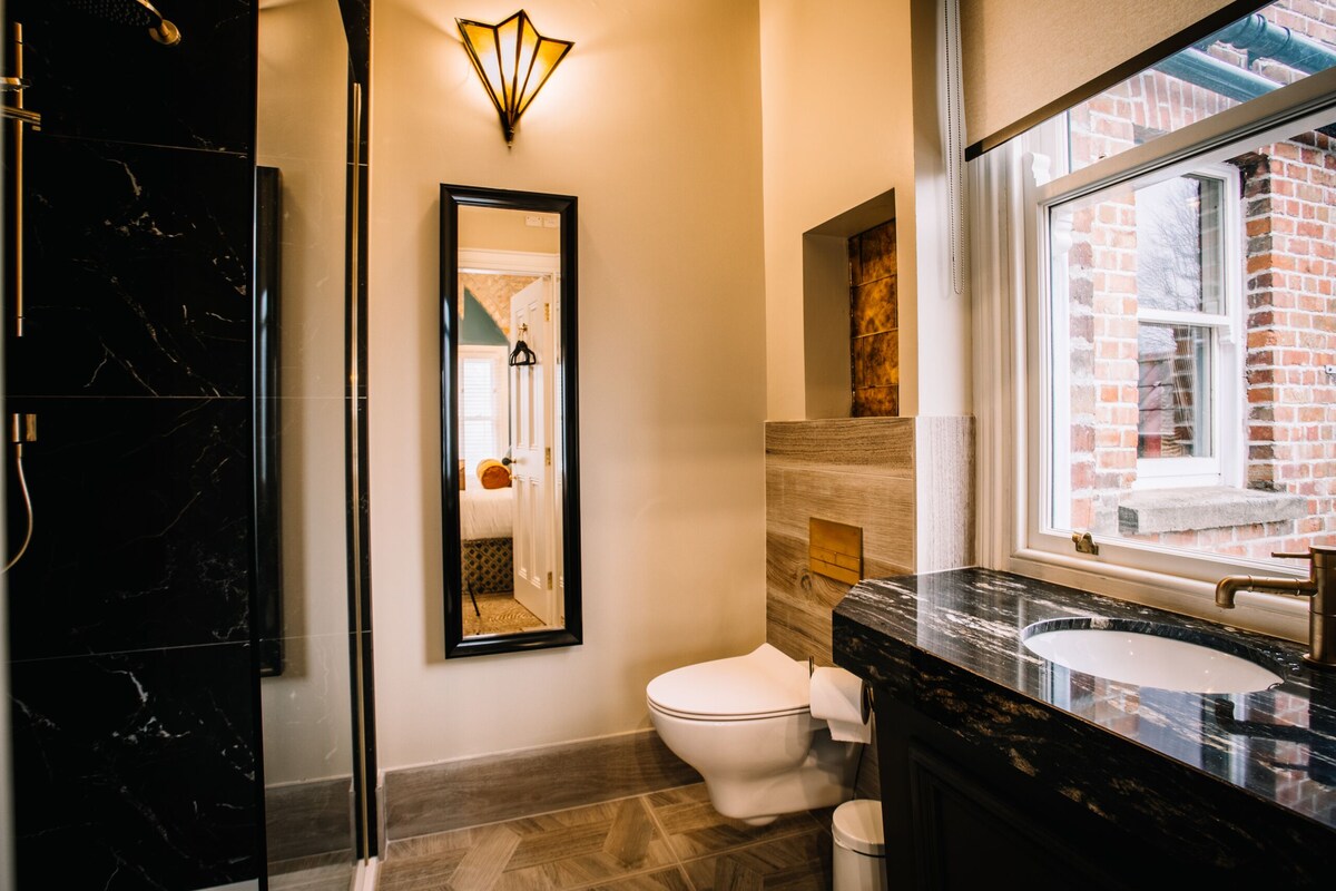 A modern bathroom with a black marble vanity, a white toilet, and a mirror.