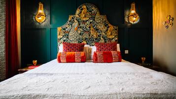 Una cama con un cabecero decorativo, dos apliques de pared y una almohada estampada en rojo y blanco.
