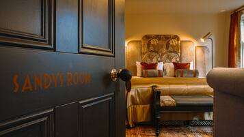 Una habitación con una cama, una silla y una puerta con la leyenda 'SANDYROOM'.