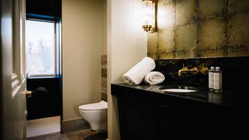 Ein Badezimmer mit schwarzer Ablagefläche, weißem Waschbecken, einem Handtuch und einer Toilette.