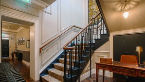 Una amplia escalera con alfombra estampada, un escritorio de madera y una silla.