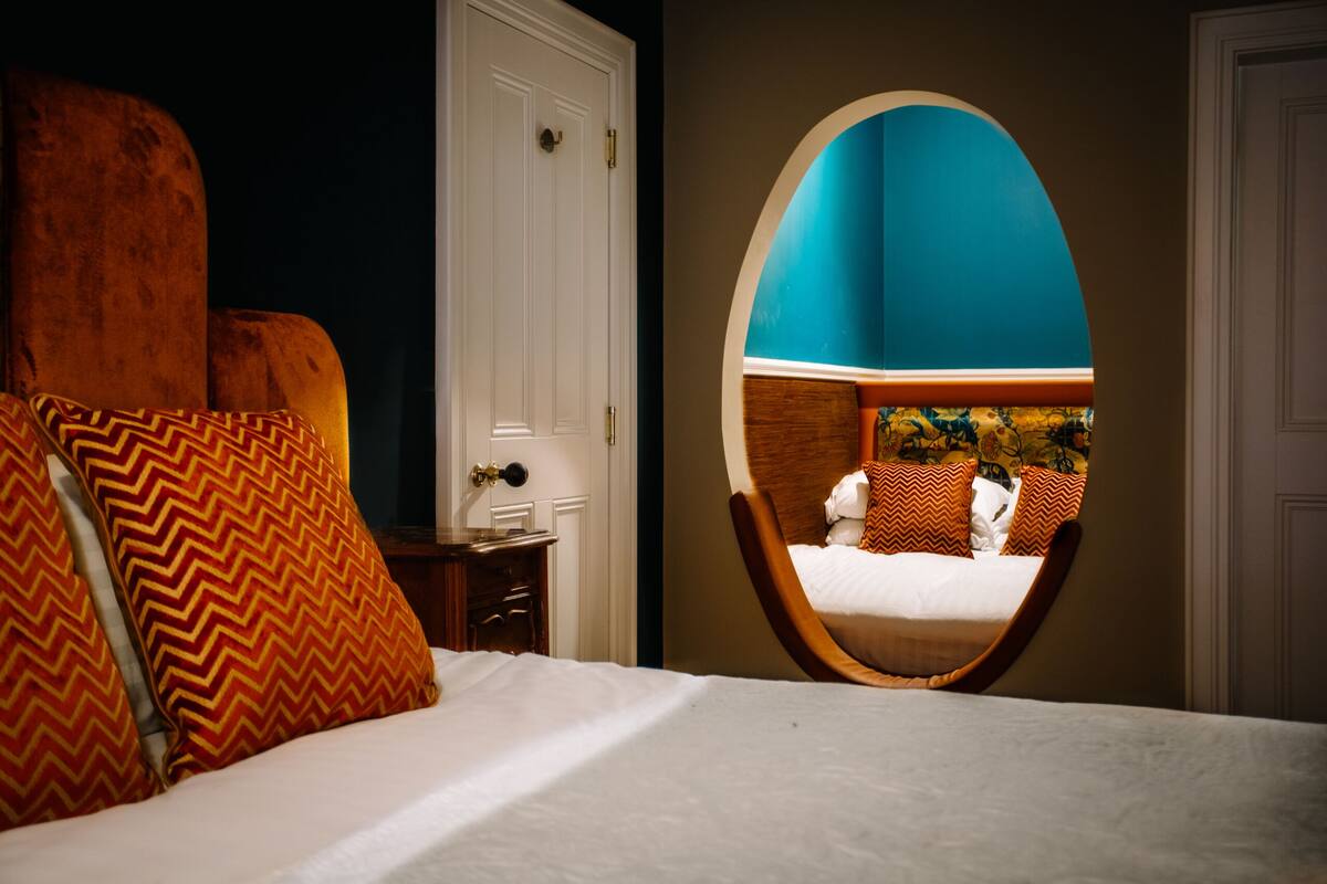 A bedroom with a bed, a mirror, and a door.