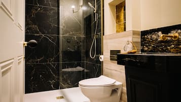 Een moderne badkamer met een marmeren douche, toilet en een wastafel met een decoratieve glazen pot.