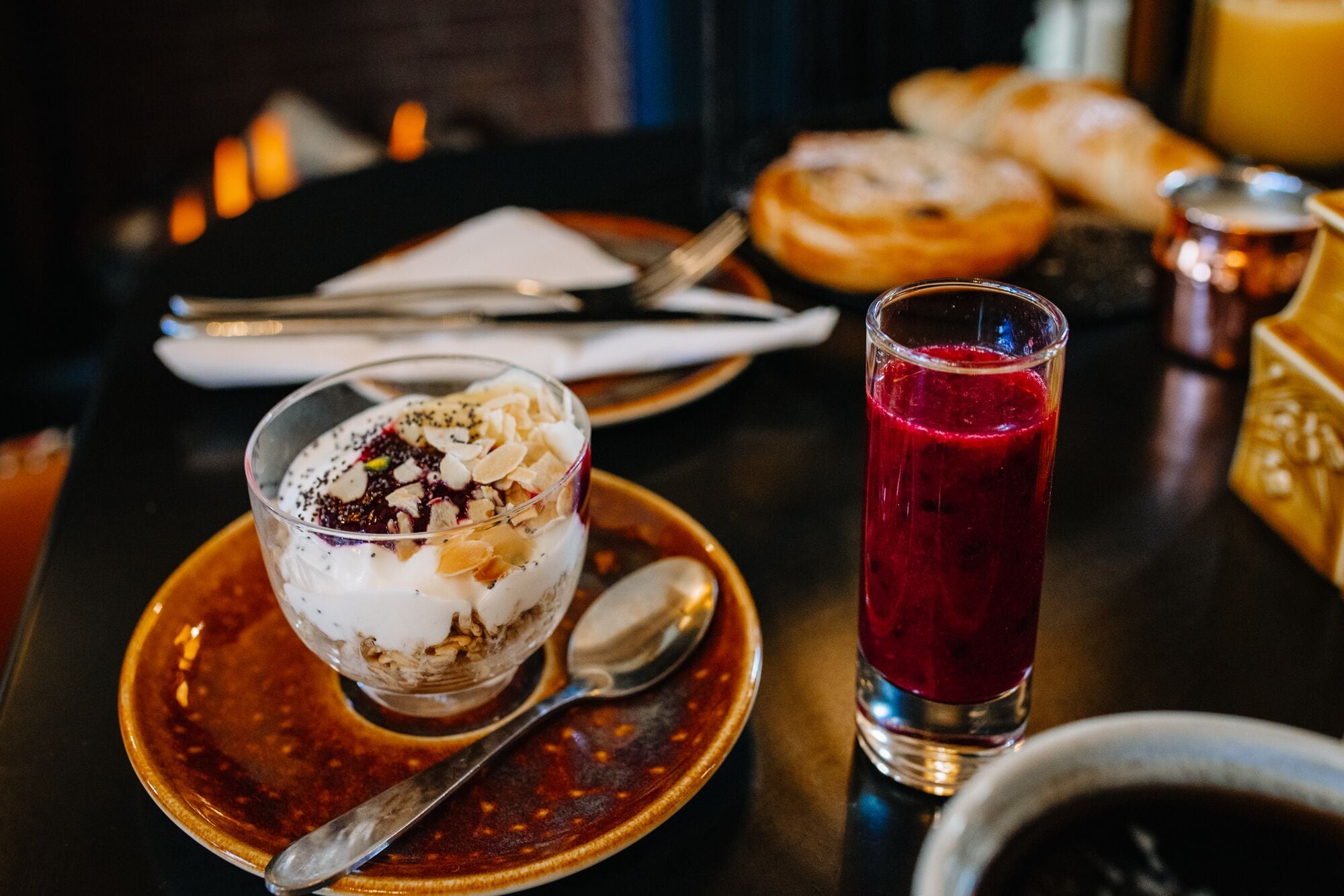 A dessert bowl with a layered dessert and a glass of red beverage on a table.