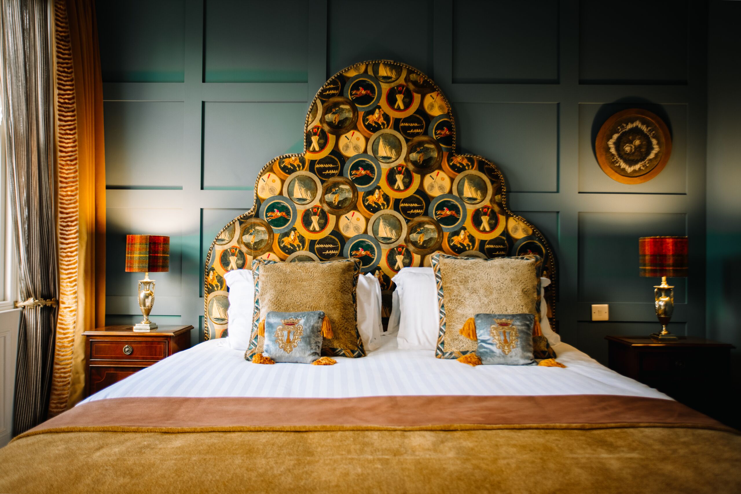 A bed with a unique headboard decorated with circular patterns, a striped bedspread, and two bedside tables with lamps.