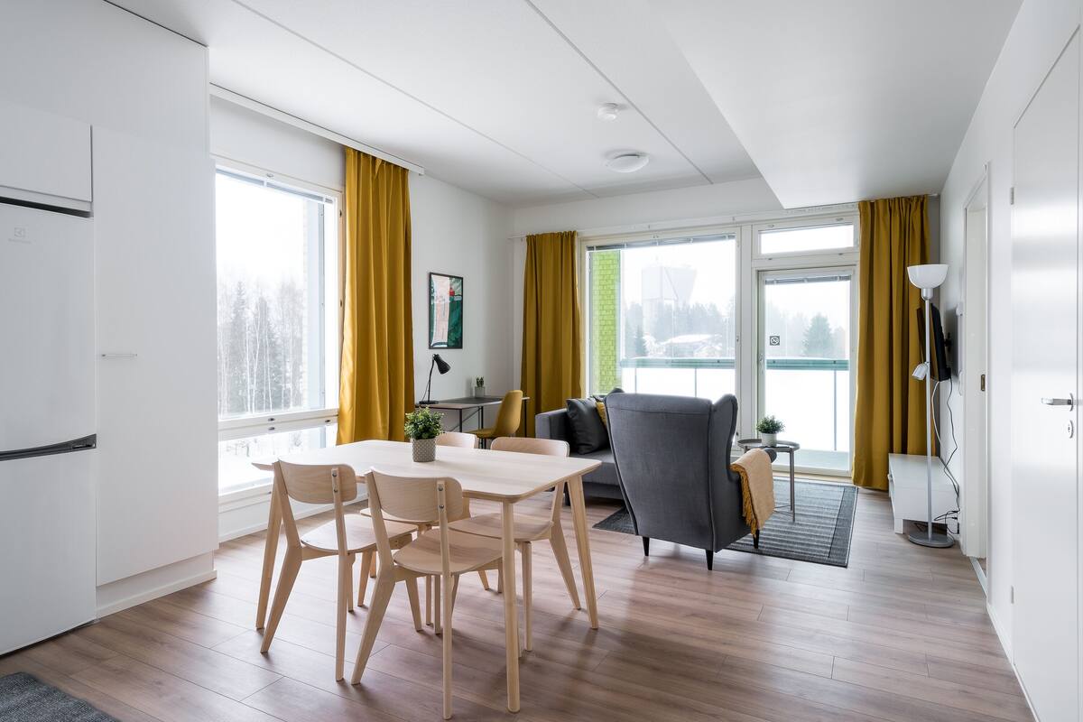 Een moderne woonkamer met een eetgedeelte, grote ramen en uitzicht op de omgeving.