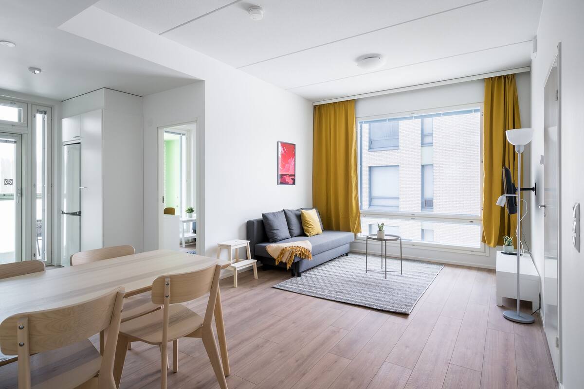 Een moderne woonkamer met een bank, een eettafel en een lamp.