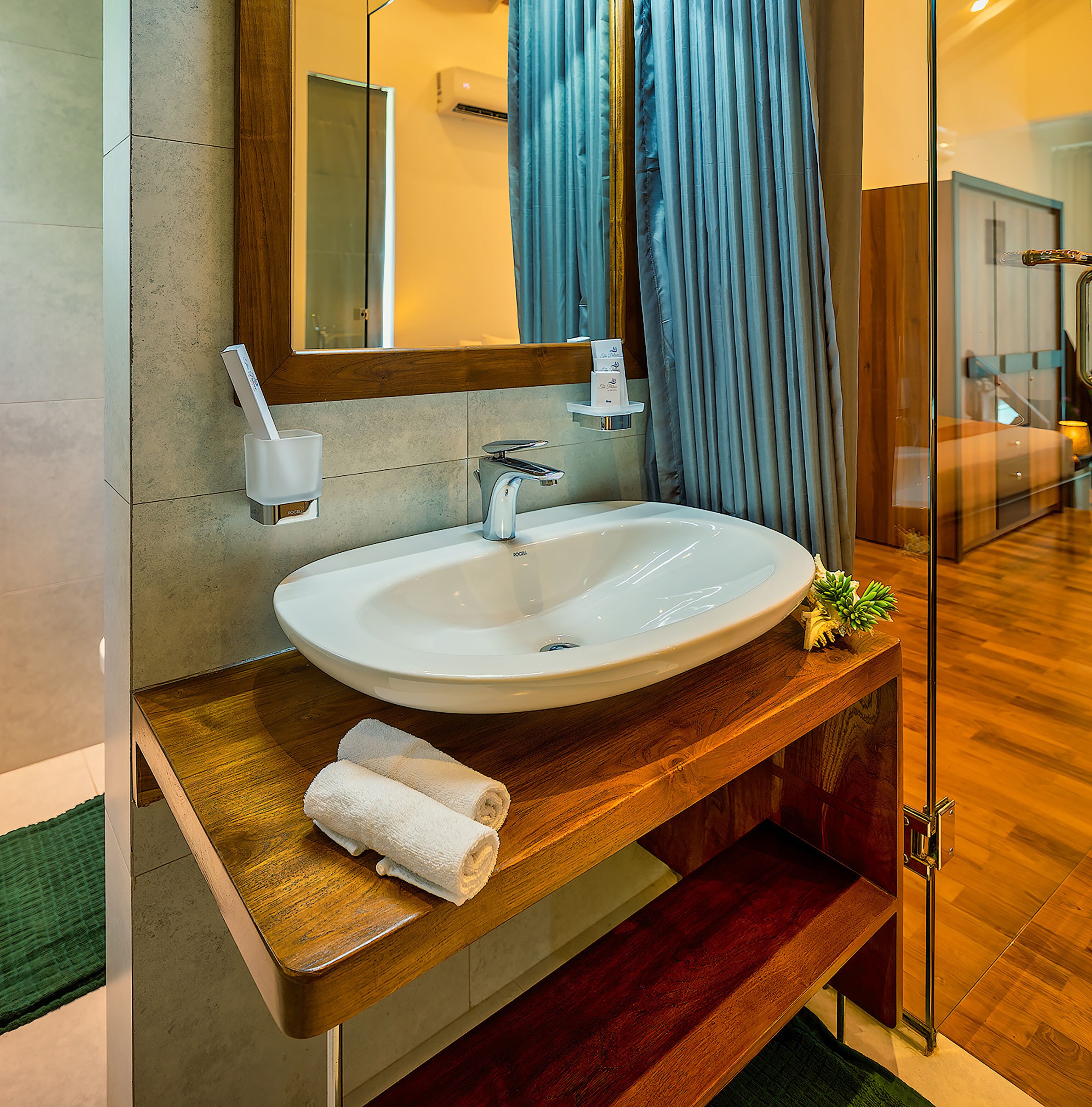 A modern bathroom with a large sink, mirror, and wooden vanity.