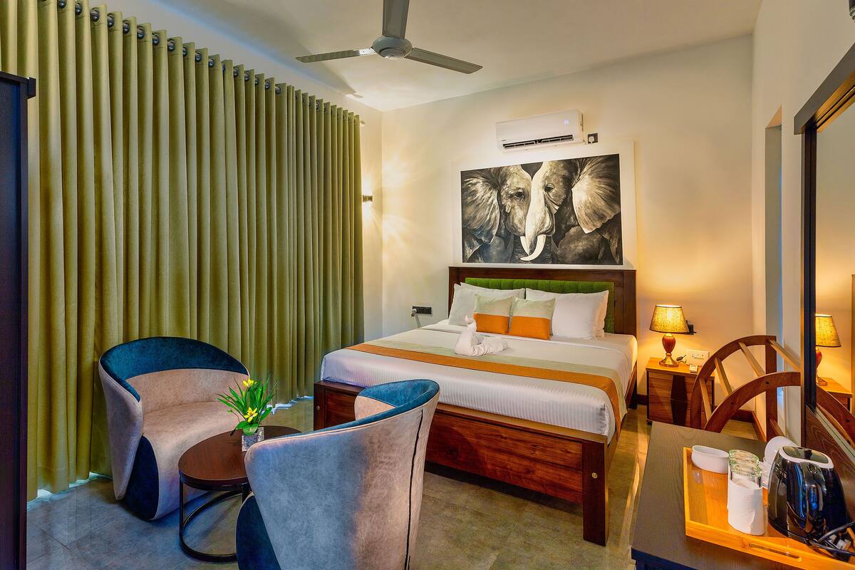 A hotel room with a bed, two chairs, a table, and a ceiling fan.