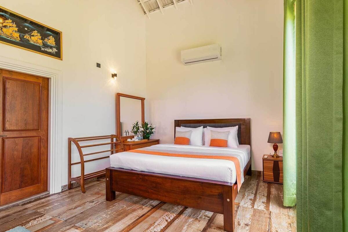 A bedroom with a wooden bed, a nightstand, a mirror, and a door.