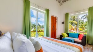 A hotel room with a large bed, a sofa, and a balcony with a view of palm trees. - The Palace by Ocean (Ahungalla)