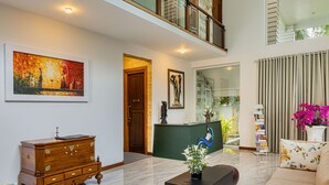 A spacious lobby with a reception desk, a wooden cabinet, a sofa, and a coffee table. - The Palace by Ocean (Ahungalla)