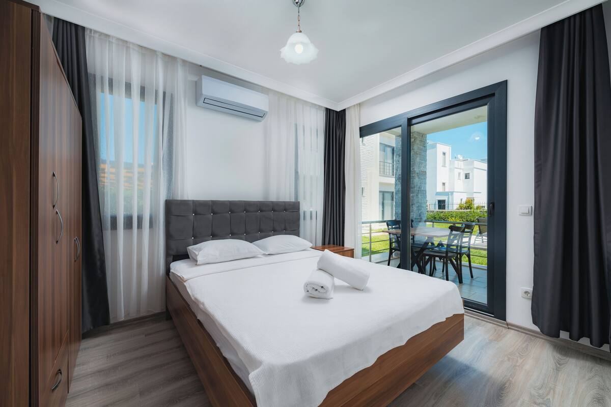 Un dormitorio moderno con una cama grande, un armario de madera y un ventanal corredera que da a un espacio exterior.