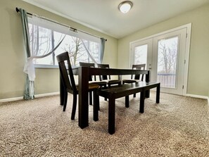 A room with a dining table and chairs, carpeted floor, and large windows with curtains. - 6268 Mullen · Among trees outside the city (Cincinnati)