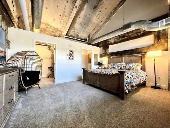 A bedroom with a wooden bed, a chair, a dresser, and a lamp.