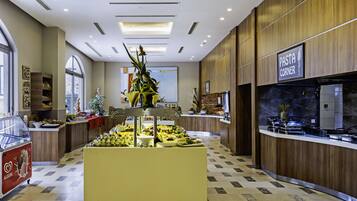 A modern hotel lobby with a central floral display, a pasta counter, and a reception area with a large window.