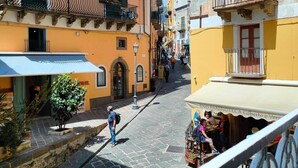 A narrow street with buildings on both sides, featuring balconies and outdoor seating areas. - Lipari Suite  (Lipari)