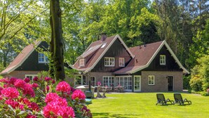 A two-story house with a brick exterior, large windows, and a well-maintained lawn with chairs. - Het Landhuis by Interhome (Losser)