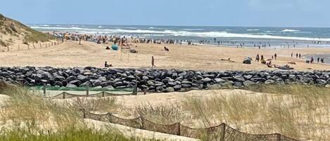 A beach with a rocky barrier and a clear sky.