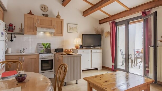 A cozy kitchen with wooden cabinets, a stove, and a dining area with a table and chairs. - L'Aquillon by Interhome (Noves)