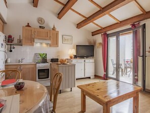 A cozy kitchen with wooden cabinets, a stove, and a dining area with a table and chairs.