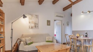 A cozy living room with a wooden table, a sofa with cushions, a floor lamp, and a bookshelf. - L'Aquillon by Interhome (Noves)