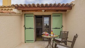 A small patio with a table and chairs, a green door, and a tiled floor. - L'Aquillon by Interhome (Noves)