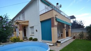 A two-story house with a swimming pool, a covered patio, and a stone wall. - Vacation home Cuco by Interhome (Cambrils)