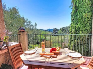A wooden table set outdoors with a view of a vineyard and mountains.