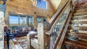 Un intérieur en bois avec un escalier, un canapé et une vue sur l’extérieur.
