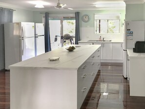 A modern kitchen with a central island, white cabinetry, and a window with a view. - Ludbrookes (Nelly Bay)