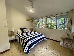 A bedroom with a bed, a nightstand, a chair, a window with a view of greenery, and a ceiling fan. - Melita (Arcadia)