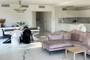 Un salon moderne comprenant un canapé, une table basse et un coin repas avec une table et des chaises.