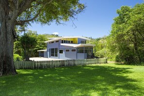 A modern two-story house with a flat roof, large windows, and a wooden fence. - Shipwreck Sands (Picnic Bay)