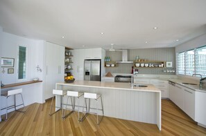 Una cocina moderna con una isla central, taburetes de bar y electrodomésticos integrados.