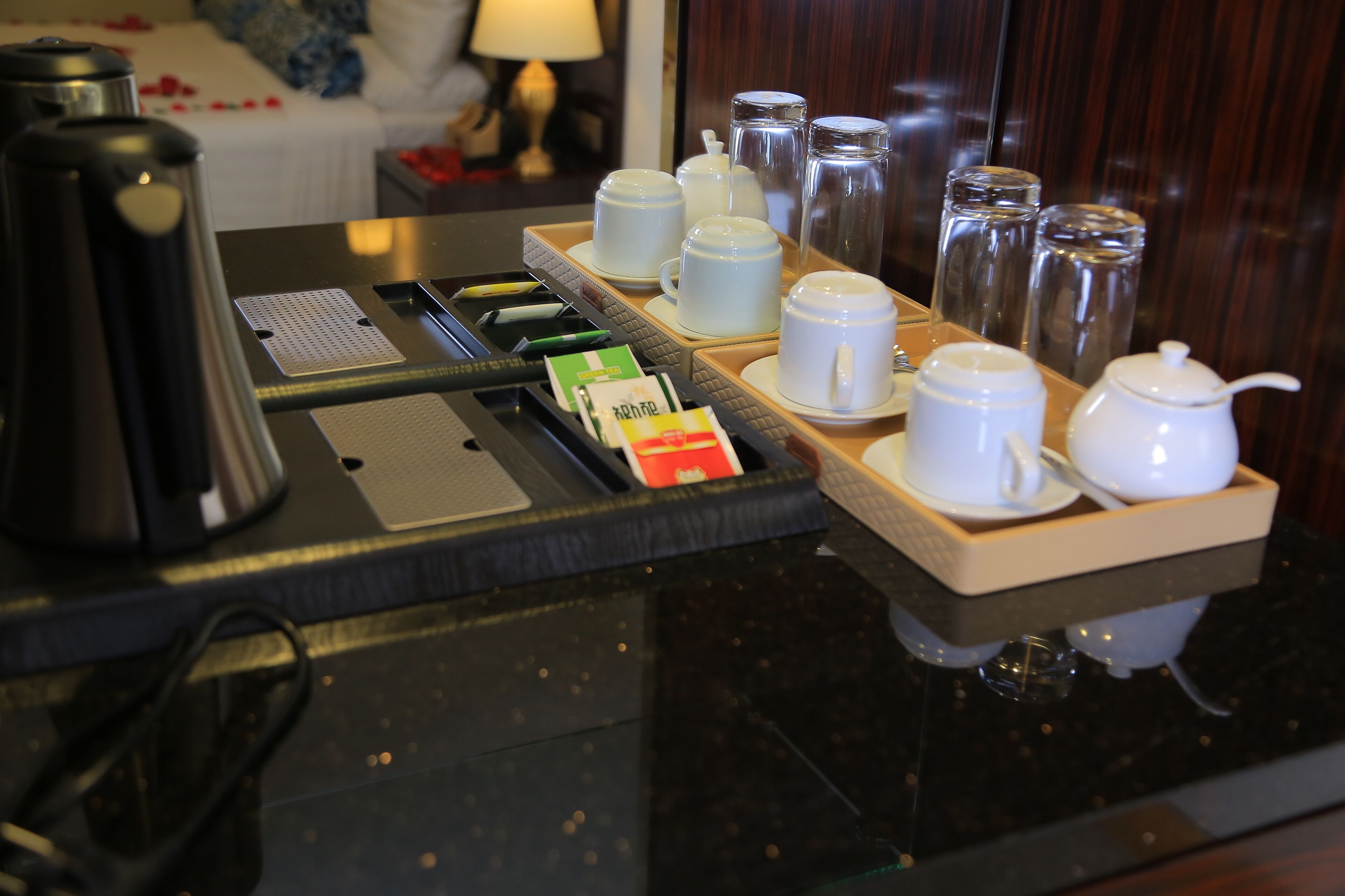 Morgenmad på hotel med kaffemaskine, kaffekopper og teposer samt sukker på en bakke.