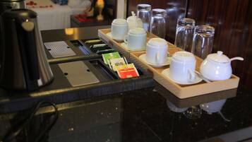 Morgenmad på hotel med kaffemaskine, kaffekopper og teposer samt sukker på en bakke.