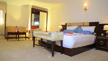 A hotel room with a bed, a bench, a nightstand, and a mirror.