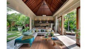Relax in a spacious room with a comfortable seating area, dining table, and lush garden views through large windows.
