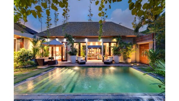 A modern house with a swimming pool, outdoor seating, and a well-maintained garden.