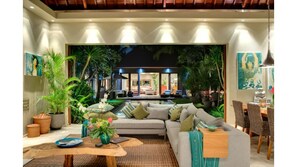 Relax in this inviting space with a comfortable sofa, coffee table, and side table, surrounded by lush greenery and natural light.
