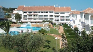 Een groot resort met meerdere witte gebouwen, een zwembad en verzorgde tuinen.