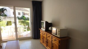 Een kleine kamer met een houten kast, een televisie en een magnetron.
